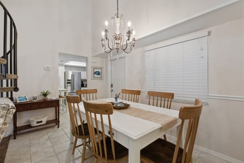 Gather and dine in this charming beach stay featuring a bright open dining space, stylish chandelier, and easy access to the kitchen. This inviting vacation rental offers coastal comfort perfect for family meals after a day by the sea.