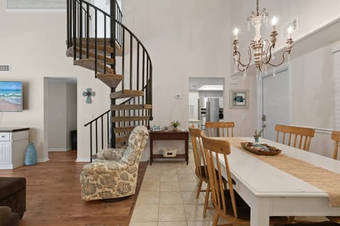 Bright and airy beach stay featuring a charming spiral staircase, coastal décor, and open dining space. This inviting vacation rental offers the perfect blend of comfort and style for your relaxing seaside getaway.