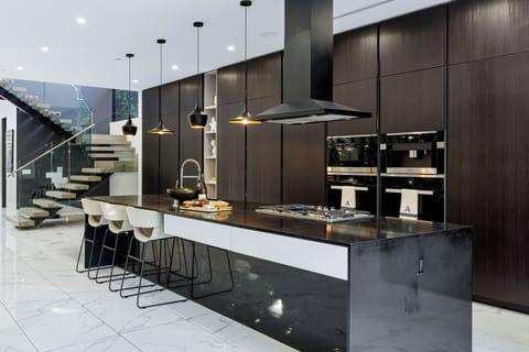 Designer chef’s kitchen with oversized waterfall island, premium appliances, and statement pendant lighting.