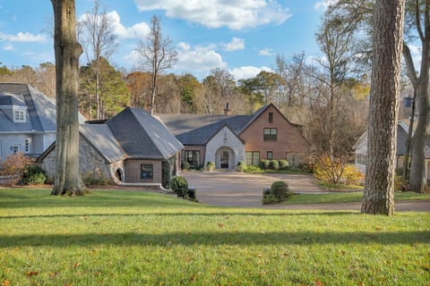 Welcoming brick exterior w/ manicured lawn & curved driveway leading to a grand entrance