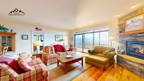 Cozy up by your stone fireplace while mountain views stretch beyond your private balcony in this warm, inviting living space.