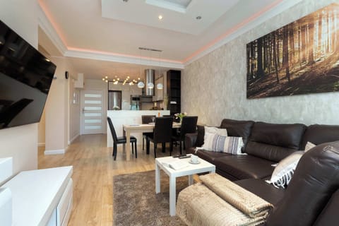 A bright open-plan living and dining area. The design features light walls, a comfortable sofa, and a stylish table setup.