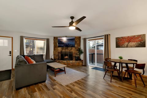 Cozy mountain living room with a stone fireplace, comfy seating, and smart TV—perfect for relaxing evenings, movie nights, and warm cabin vibes after outdoor adventures.