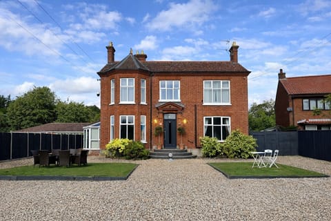 Red-brick house with gravel drive and front lawn.