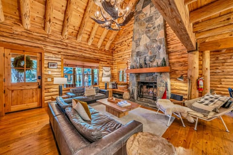 Living room: Wood-burning fireplace, leather seating, vaulted log ceiling