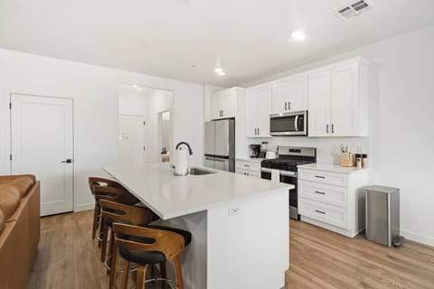 Bright modern kitchen with large island, bar seating, and stainless steel appliances.