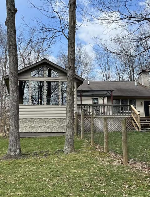 Exterior view of the house with large floor-to-ceiling windows, beige siding, and a fenced grassy yard.