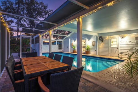 Relax in this stylish backyard oasis featuring a private pool, covered patio, and outdoor dining under warm string lights. Perfect for evening swims, alfresco meals, and unforgettable nights in a serene, resort-style setting.