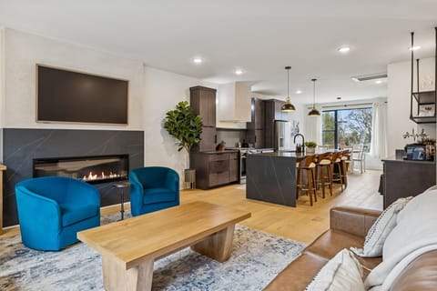 Living Room: Experience sophisticated living. From the sleek fireplace feature to the inviting sofa and fully-equipped kitchen, every detail in this space is curated for your ultimate comfort and enjoyment.