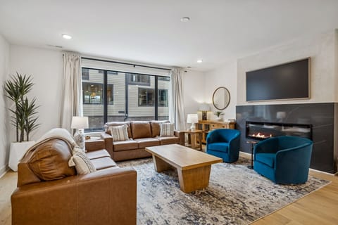 Living Room: Experience sophisticated living. From the sleek fireplace feature to the inviting sofa and fully-equipped kitchen, every detail in this space is curated for your ultimate comfort and enjoyment.