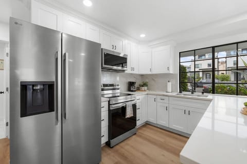 Whip up beach-day bites in this stunning kitchen featuring stainless steel appliances, marble backsplash, and a sunlit bay window. A modern Crown Point Airbnb just a short walk from the San Diego coast.