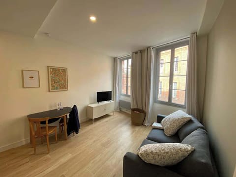 Salon lumineux avec canapé confortable, coin bureau et vue sur les façades en brique toulousaines