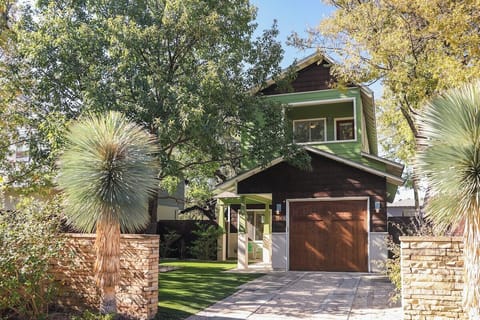 Charming property entrance features stone pillars and tropical palms, creating an inviting arrival experience in this tree-lined neighborhood setting.