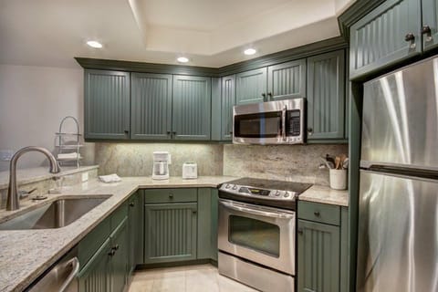 Cook up a storm in the modern kitchen, equipped with stainless steel appliances, sleek green cabinetry, and all the essentials for preparing delicious meals.