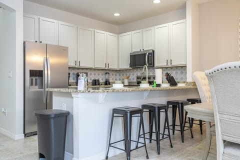 Bright modern kitchen with sleek stainless steel appliances and breakfast bar seating