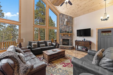 Sink into luxurious leather seating by your crackling stone fireplace, watching the forest through soaring windows in this mountain retreat.