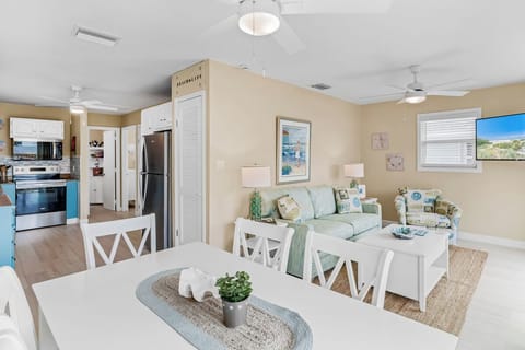 Your open living space flows seamlessly from dining to kitchen, where coastal décor and natural light create a welcoming retreat.