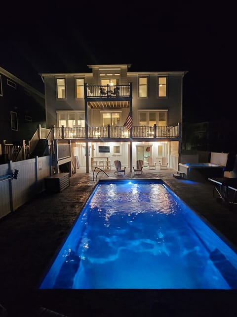The illuminated property and sparkling pool create a stunning nighttime scene, showcasing the vacation rental's welcoming exterior and inviting outdoor amenities for evening relaxation.