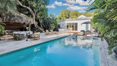 Your tropical oasis awaits with crystal-clear pool waters reflecting swaying palms, cozy thatched lounge, and modern villa surrounded by lush greenery.