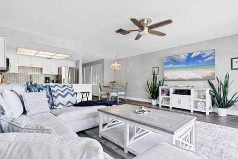 Relax in your coastal-themed living space featuring comfortable seating, modern kitchen access, and beach artwork that brings vacation vibes indoors.