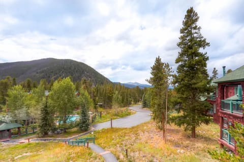 Peaceful mountain view of Soda Springs Townhomes surrounded by pine trees and winding paths under a bright alpine sky.