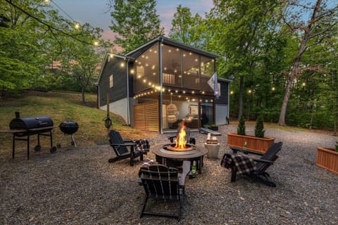 The back yard is a wooded retreat with fire pit, string lights, spa, & games