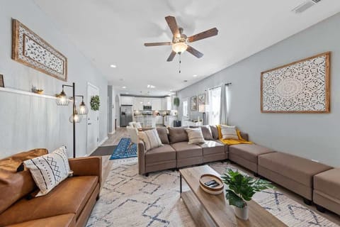 Bright living room w/ sectional seating, TV & large windows bringing in natural light