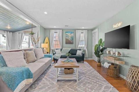 Bright living room w/ cozy seating, TV & large windows letting in plenty of natural light