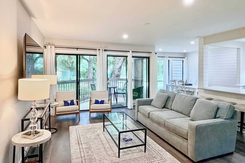 Modern living room with large sliding doors opening to a wooded balcony.