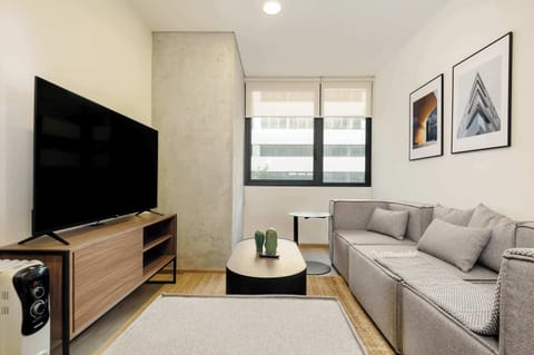 Bright and modern living room with comfortable seating and a TV, perfect for relaxing after a day in the city.