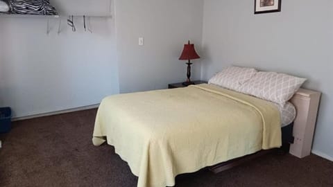Bedroom with bed, open closet, side table, and lamp