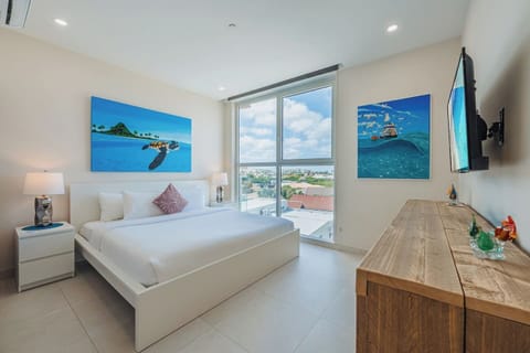 Bedroom 1 features a luxurious king-size bed, smart TV, and large windows with beautiful views. Bright, modern, and designed for comfort—perfect for restful nights after island adventures.