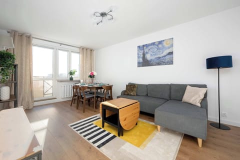 Bright living room with a comfortable sofa, TV, and dining area by large windows