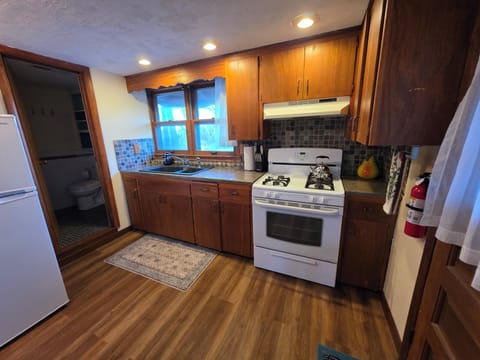 Equipped kitchen with fridge, stove, oven, microwave and dishes.