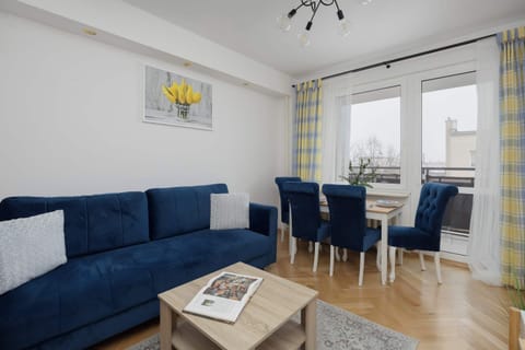 Natural daylight flowing through large windows highlights the bright interior, while the comfortable sofa and dining table create a perfect space to relax and enjoy meals together.