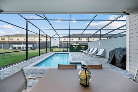 Step outside to your private oasis, featuring a screened-in pool surrounded by sleek lounge chairs. Enjoy the tranquil vibe created by the soft blue water and the expansive green lawn, perfect for relaxation and fun in the sun.