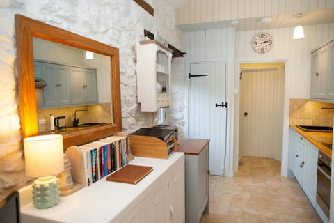 Kitchen view showing sink, countertops, open shelves, and a wall clock
