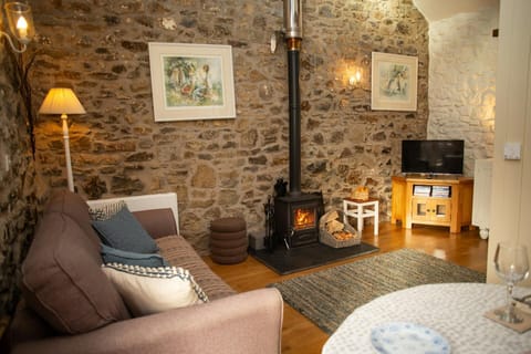 Living room with stone walls, wood-burning stove, sofa and television