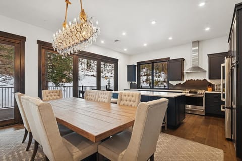 Gather around this stunning dining table where crystal chandelier light dances across the room as you share meals with mountain views through every window.