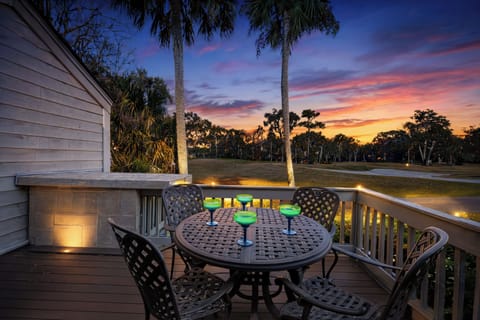 The deck overlooks a manicured golf course framed by tall palm trees and lush coastal greenery, offering open views and a sense of privacy