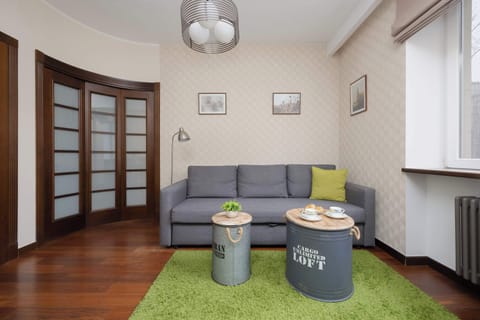 Bright and cozy bedroom furnished with a sofa, green rug, and wooden flooring.