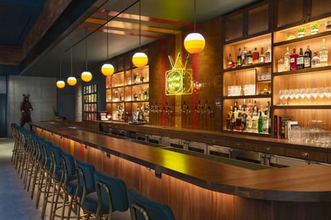 Long bar lined with taps, bottles, and glowing retro lamps