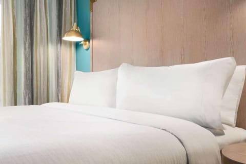 Close-up of bed with white sheets and lamp
