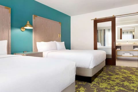 Two queen beds with teal wall and reading lights