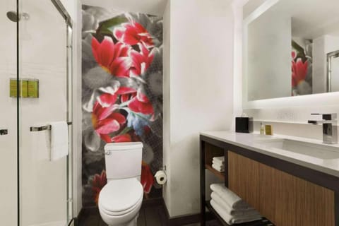 Bathroom with floral wall design, glass shower, and sleek vanity.