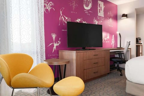 Bedroom with magenta wall, TV, and yellow chairs.