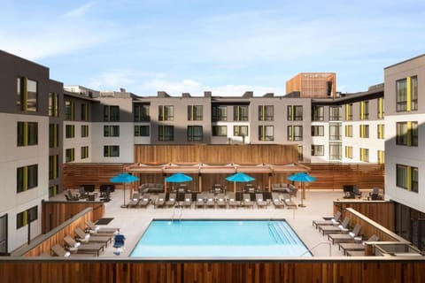 Courtyard pool with wooden deck and rows of sun chairs.