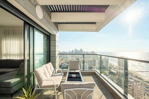Elegant balcony lounge opens through glass doors, curated seating delivers elevated indoor-outdoor living