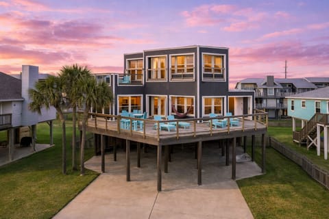 Luxury beachfront Galveston home exterior with elevated design, spacious driveway, and stunning sunset views near the Gulf of Mexico.