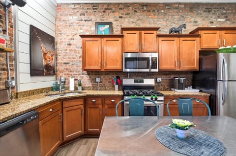 We set up a dedicated coffee bar area on the counter with a Keurig and mugs ready to go. The industrial pipe shelving above displays cool local art and glassware.